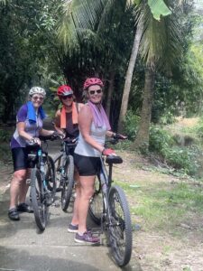 Tree Women on Bikes in Wooded Area.
